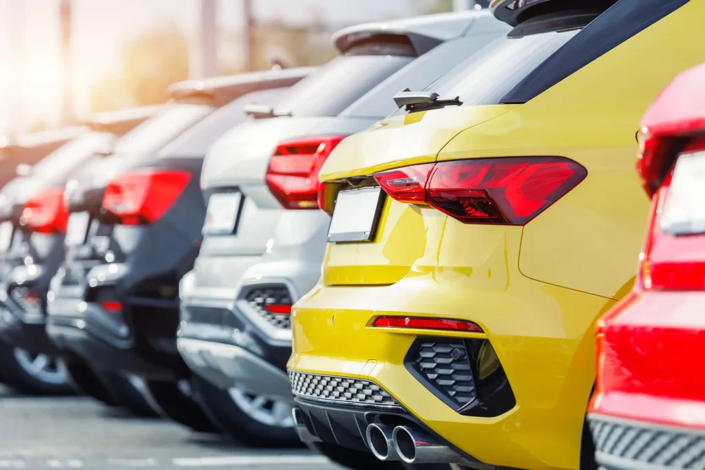 Row of parked fleet vehicles in a car yard, including a yellow hatchback, for business fleet leasing